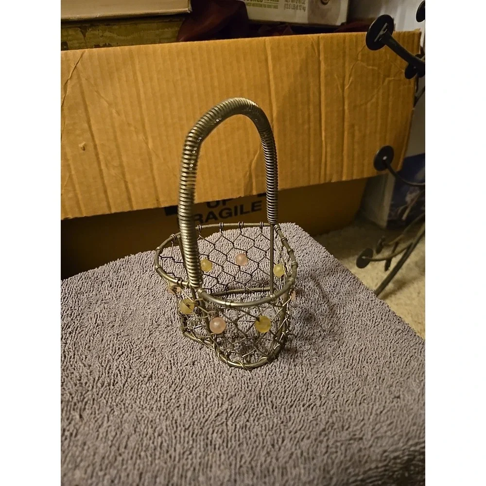 silver-tone wire basket featuring a heart-shaped base and a‎ coiled wire handle